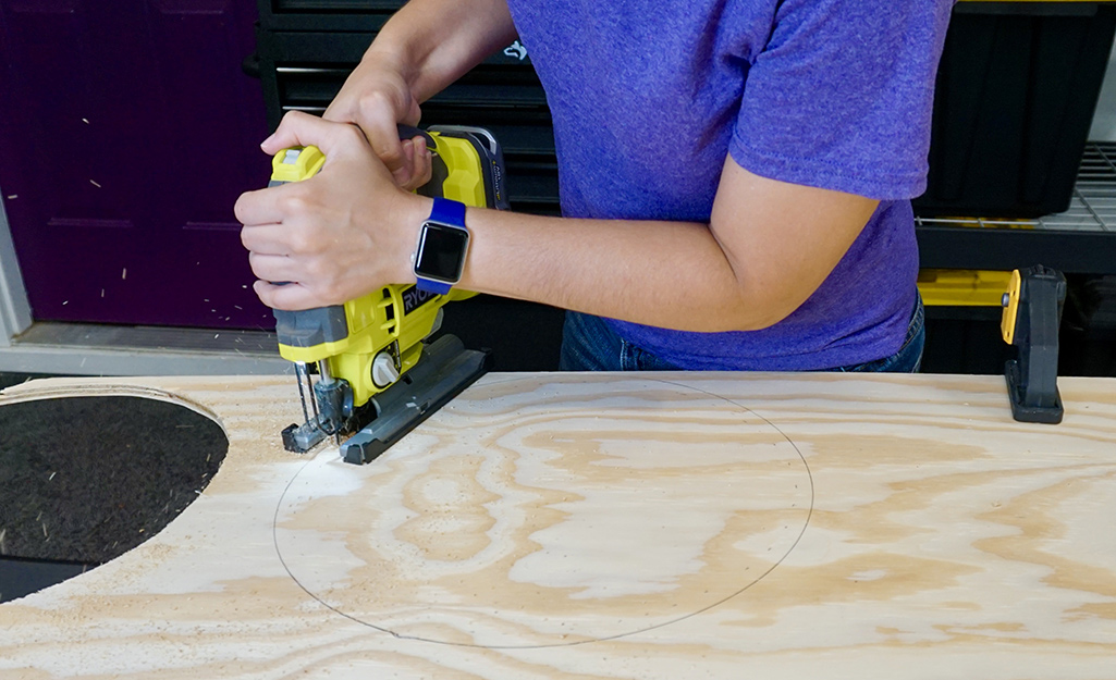 A person cutting a wood circle with a jigsaw. A person cutting a wood circle with a jigsaw.