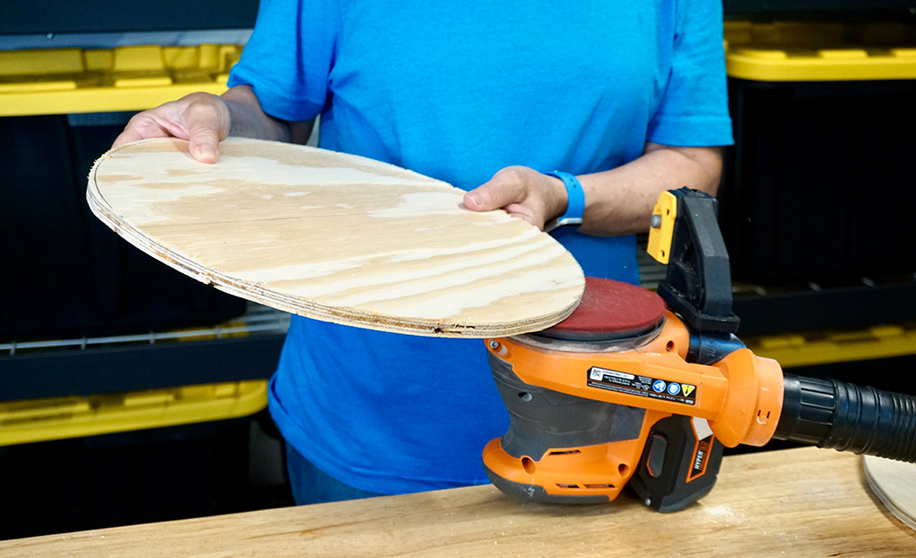 A person sanding a wood circle. A person sanding a wood circle.