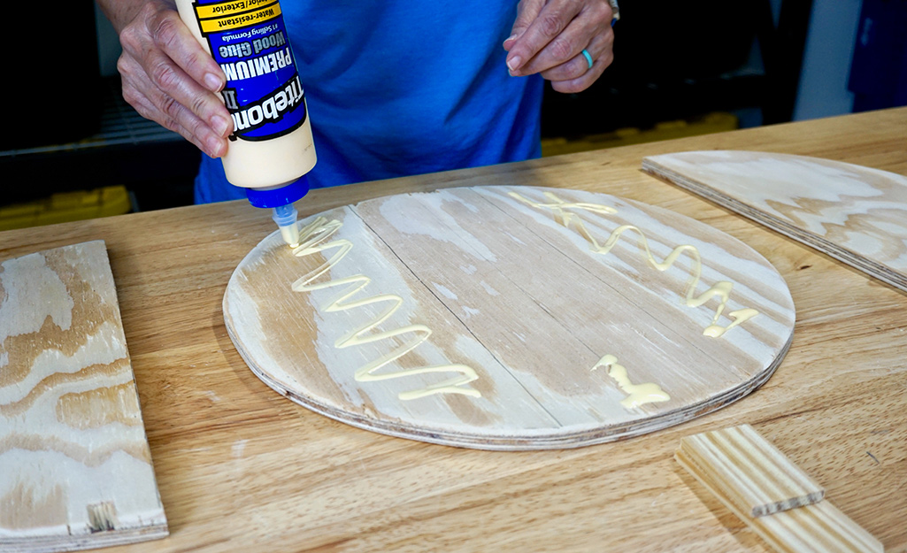A person applying wood glue to the surface of a wood circle. A person applying wood glue to the surface of a wood circle.