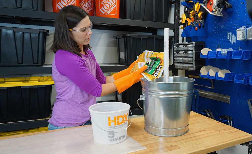 A person setting a PVC pipe with fence-post mix. A person setting a PVC pipe with fence-post mix.