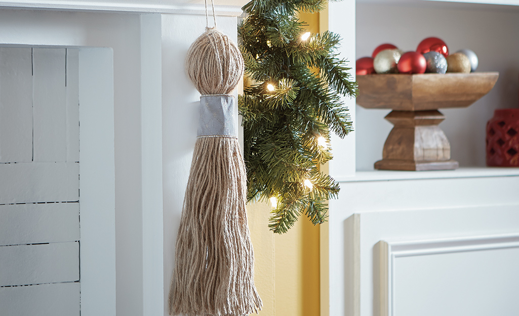 A natural twine tassel hanging on a mantel.
