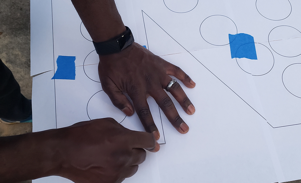 A person making a paper stencil letter.