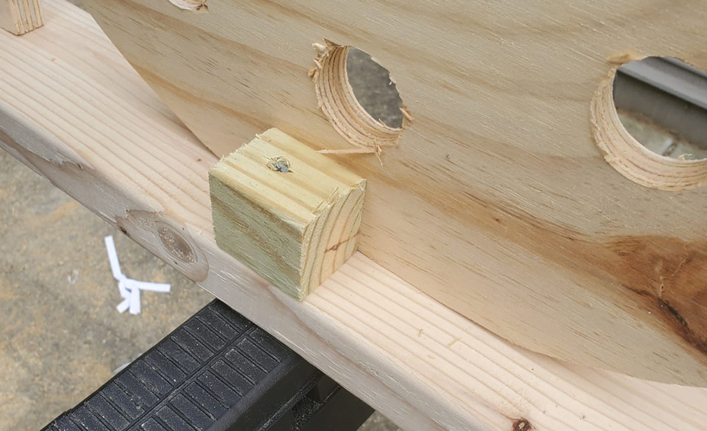 The base of the sign, showing a small block supporting a plywood letter.