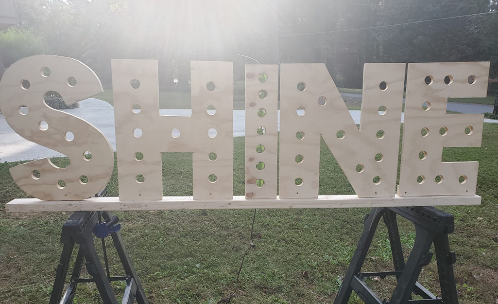 A plywood letter sign that reads "SHINE."