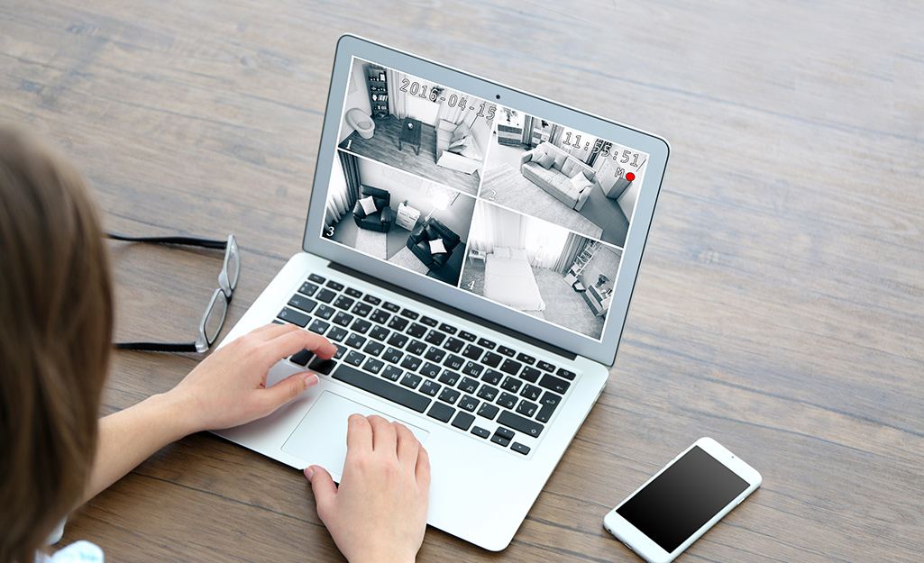 A person viewing security cameras on a laptop.