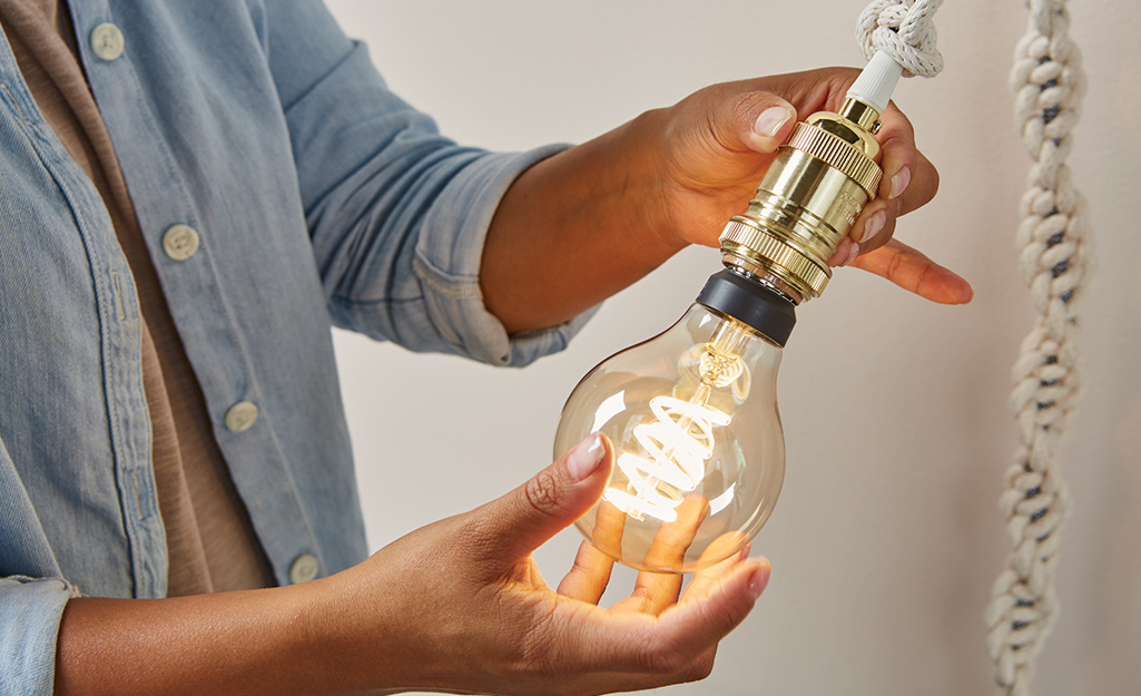 Someone adding decorative bulb to a finished macrame pendant light. Someone adding decorative bulb to a finished macrame pendant light.