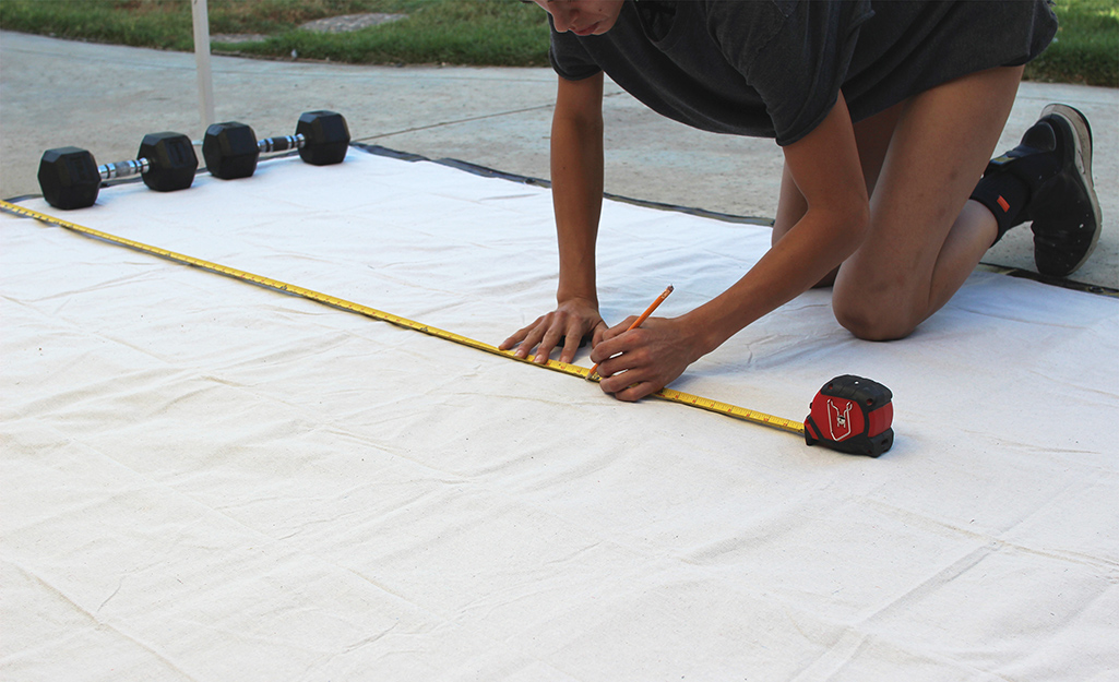 A person measuring the length of a DIY projection screen.