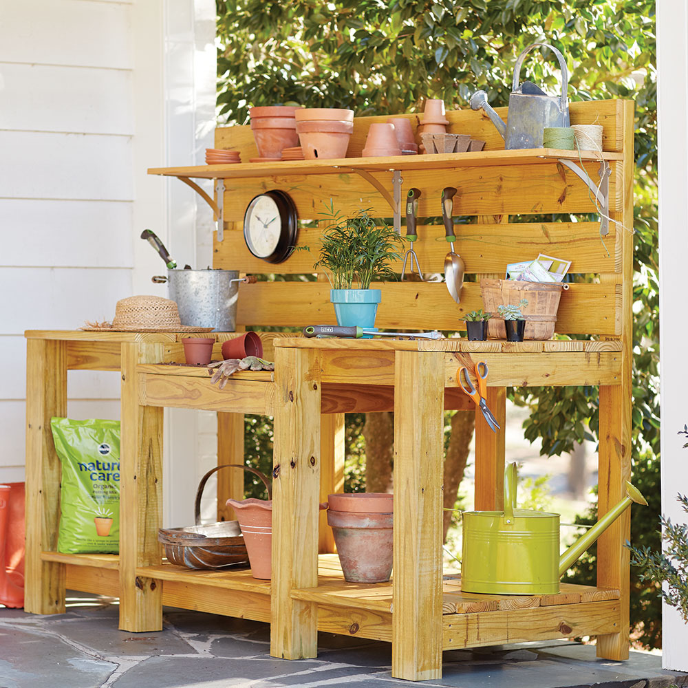 A DIY potting bench holding potting soil, plant pots and various garden tools.