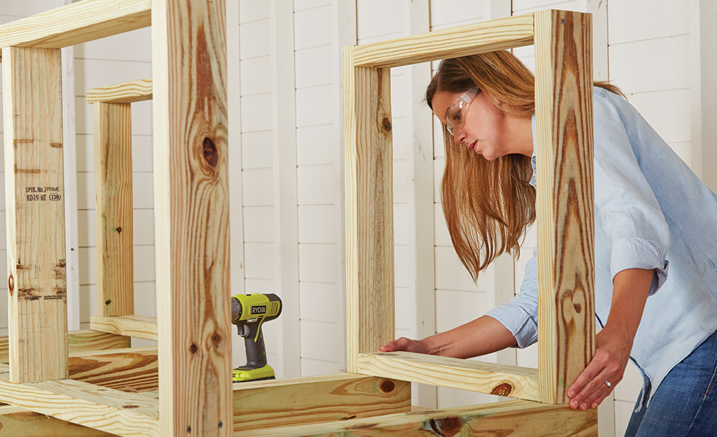 A person aligning the edges of the frames that make up the base of the potting bench.