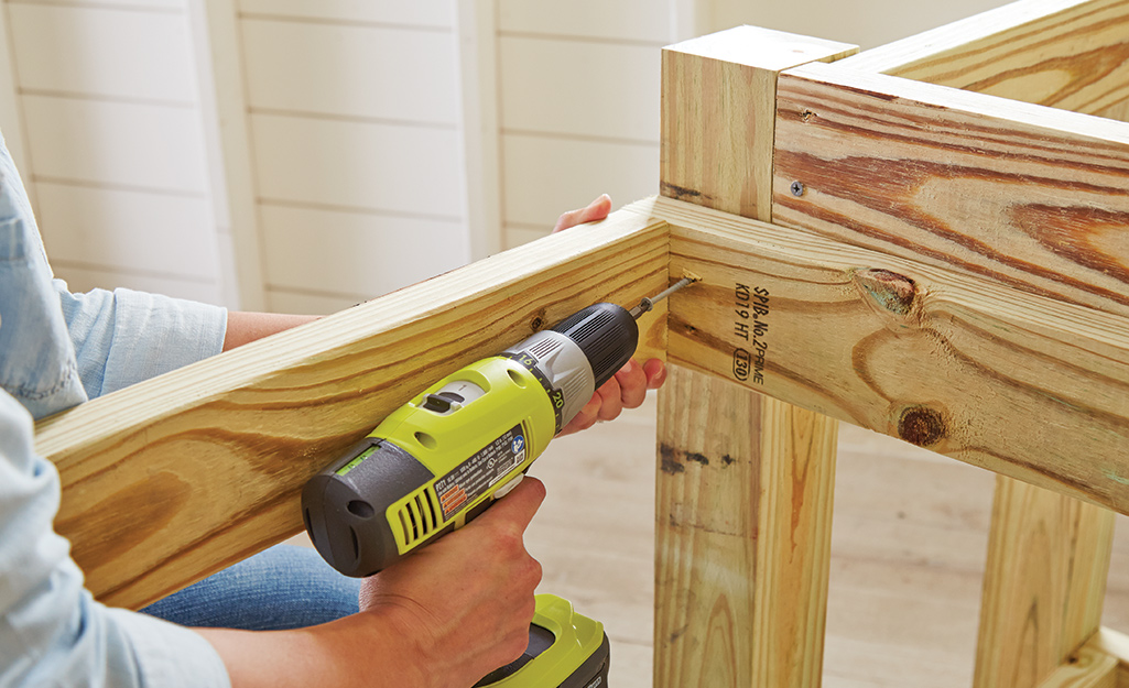 A person using a power drill to secure the potting bench frame.