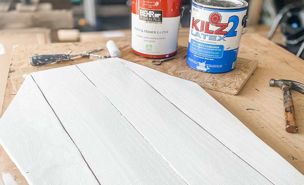 Two cans of paint and tools lay near painted fence pickets.