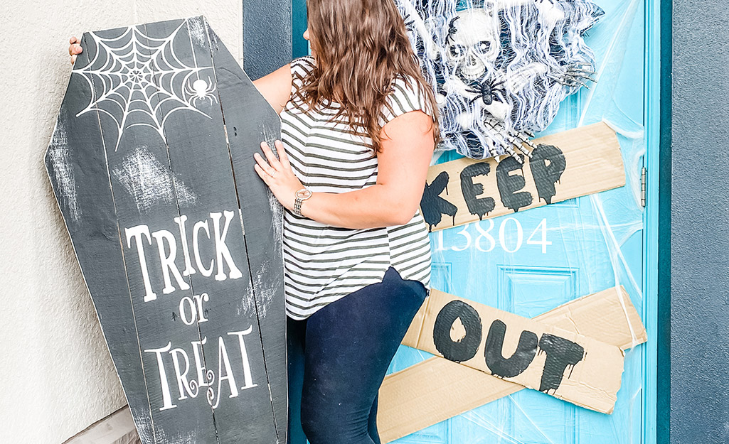 A woman decorates a front porch with her DIY sign.