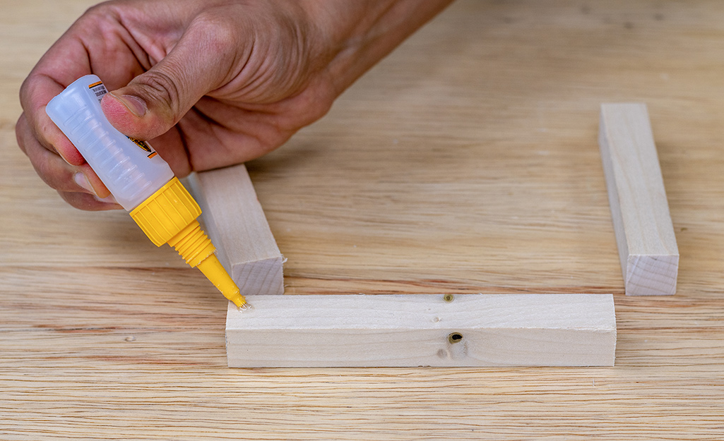 A person's hand applying glue to a dowel.