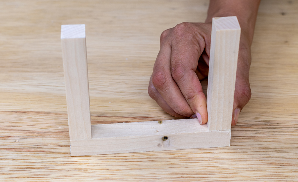 A person attaching the frame of a plant hanger.