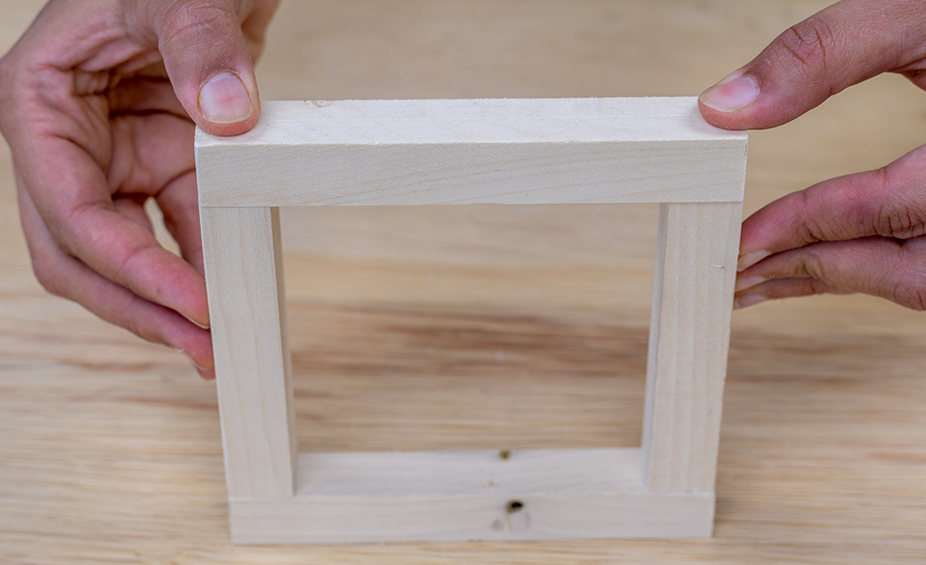 A person attaching the frame of a plant hanger.