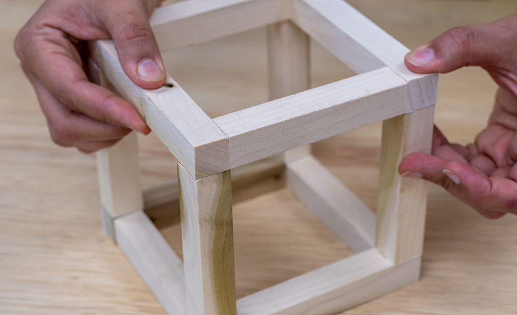 A person attaching the frame of a plant hanger.