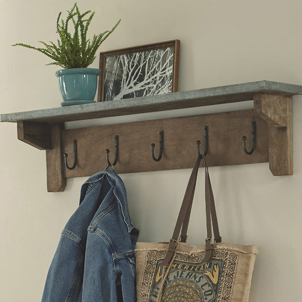 A wall shelf with five hooks holding a back, jacket, plant and frame.