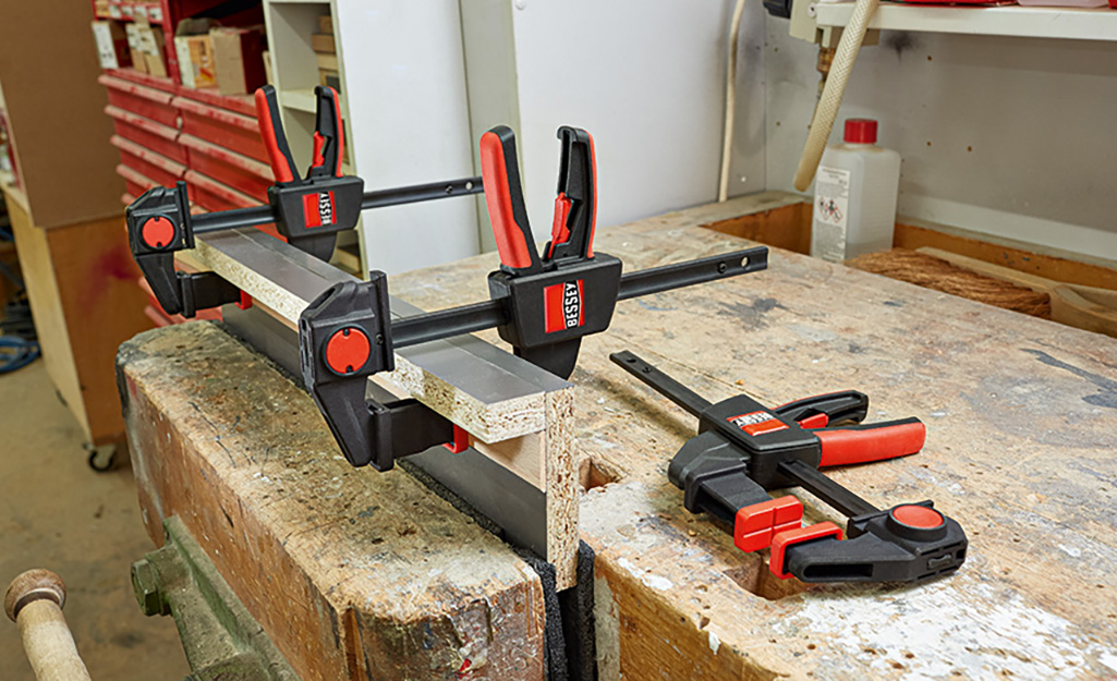 A clamp holding boards glued together in place.