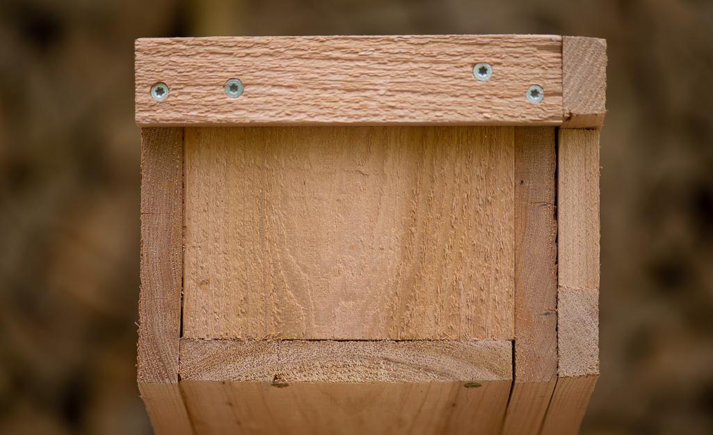 A handle is attached to the end of a DIY window box with screws. 