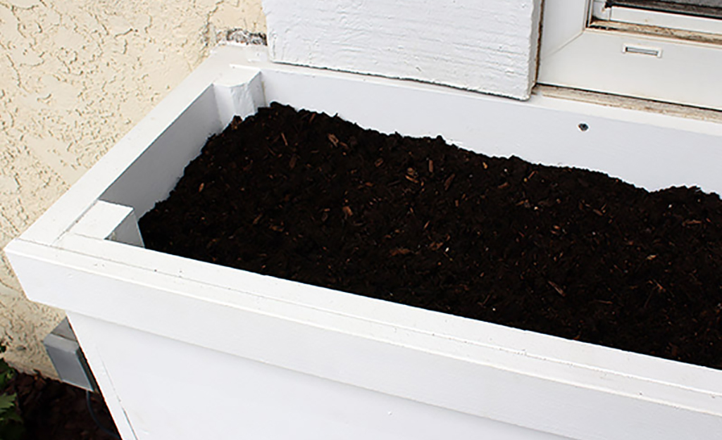 A window box planter with soil ready for planting.