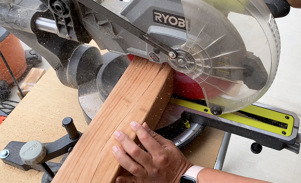 A person uses a miter saw to cut 4 x 4 boards.