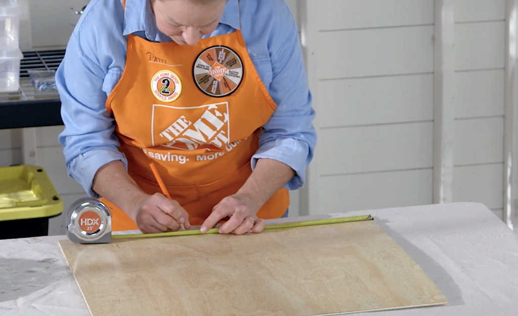 A person measures and marks wood.