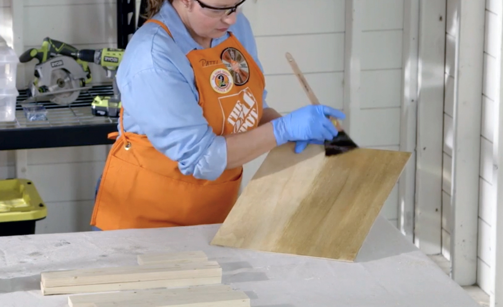 A person stains boards.