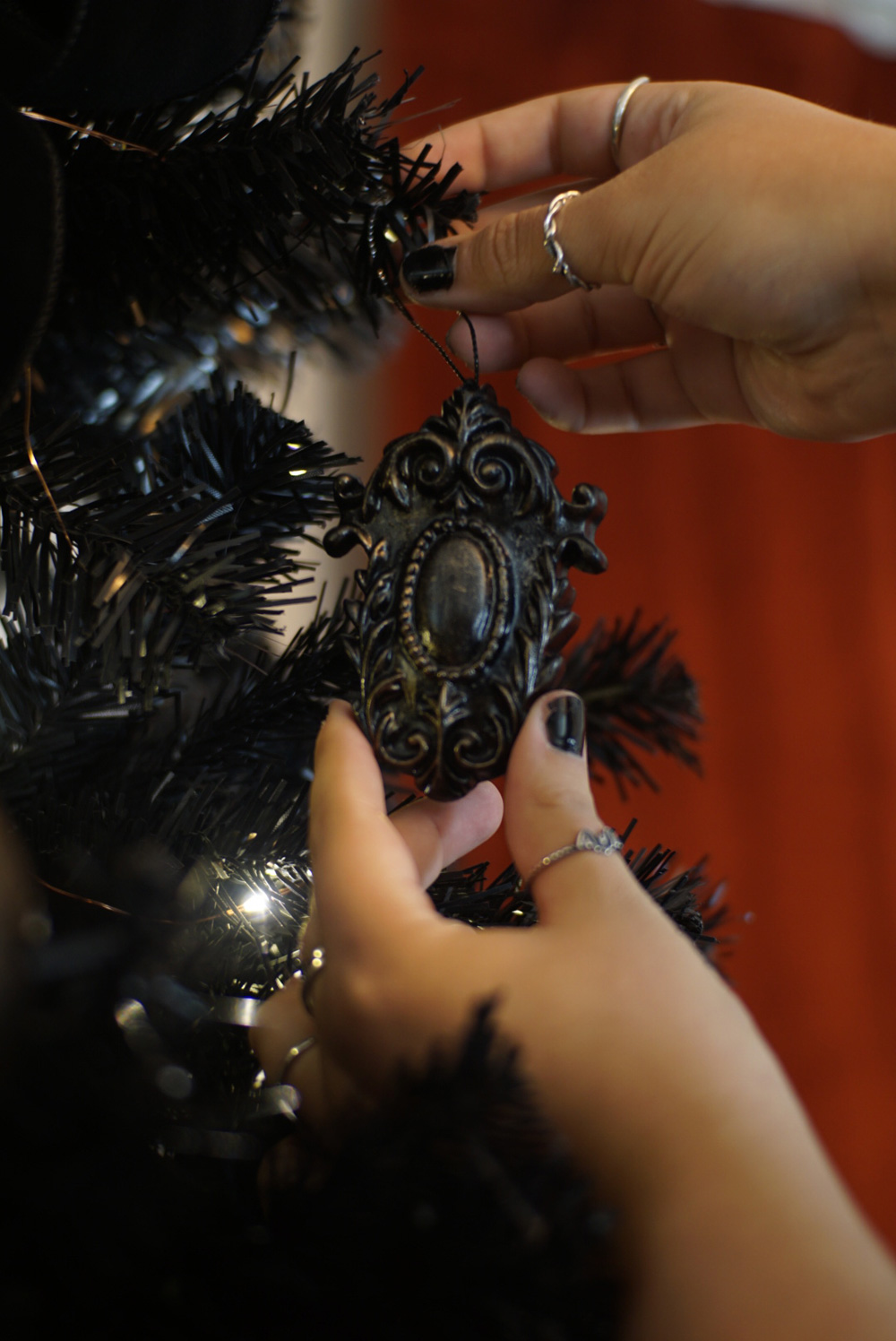 A person hanging a black ornament on a Christmas tree.