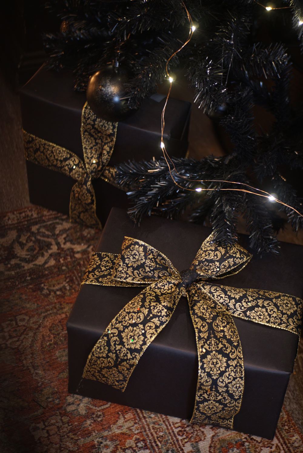 Black gift boxes with gold patterned ribbon.