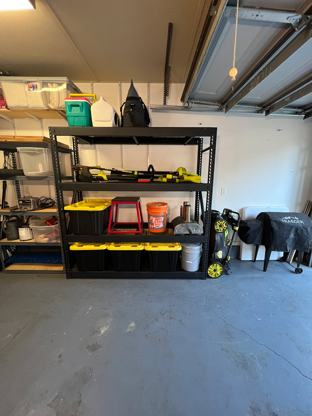 Husky brand black shelf unit with the Home Depot bucket and miscellaneous items stacked on shelves. 