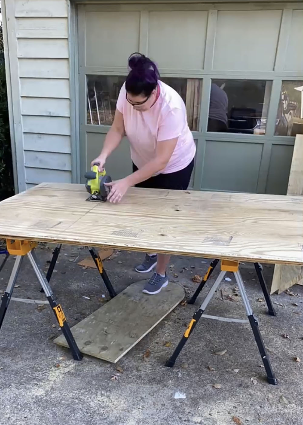 A woman cutting plywood with a circular saw.