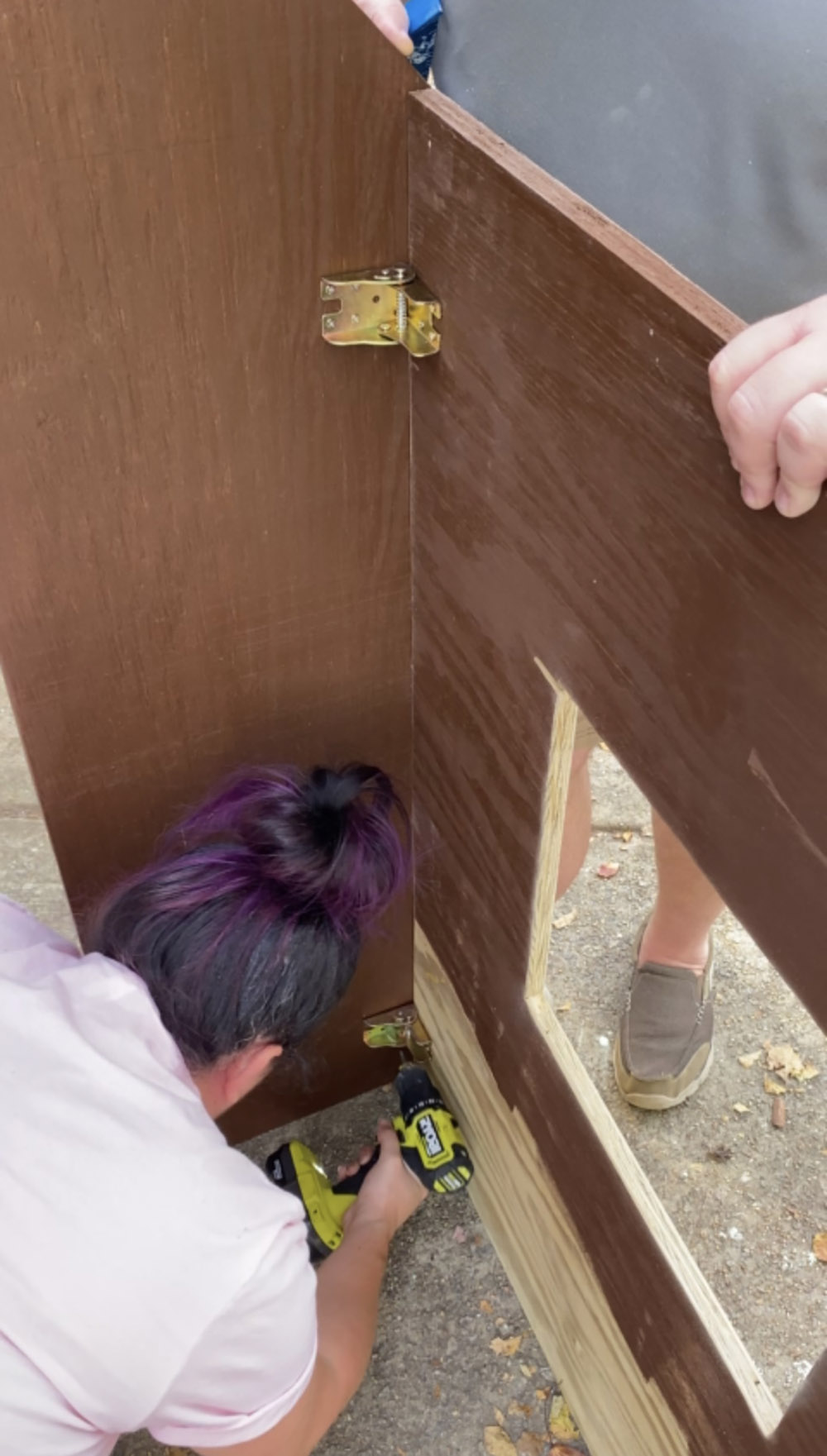 A woman drilling hinges into the cut pieces of plywood.