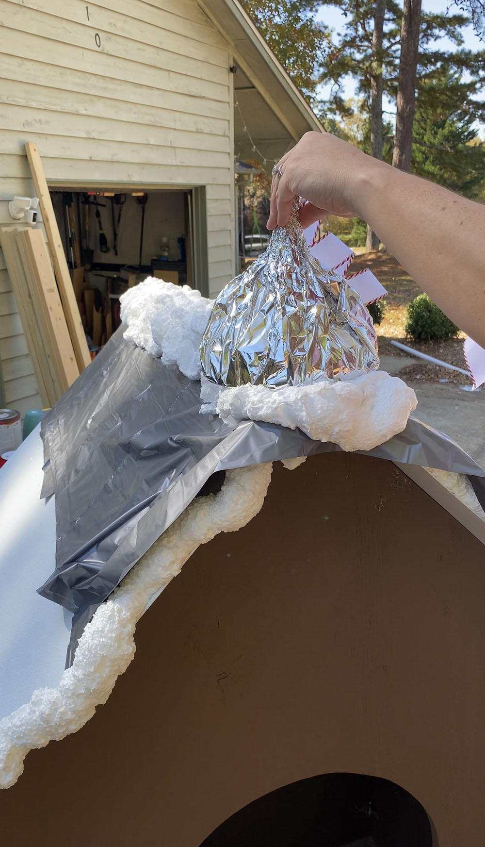 The roof of the gingerbread house being assembled with spray foam and a plastic sheet.