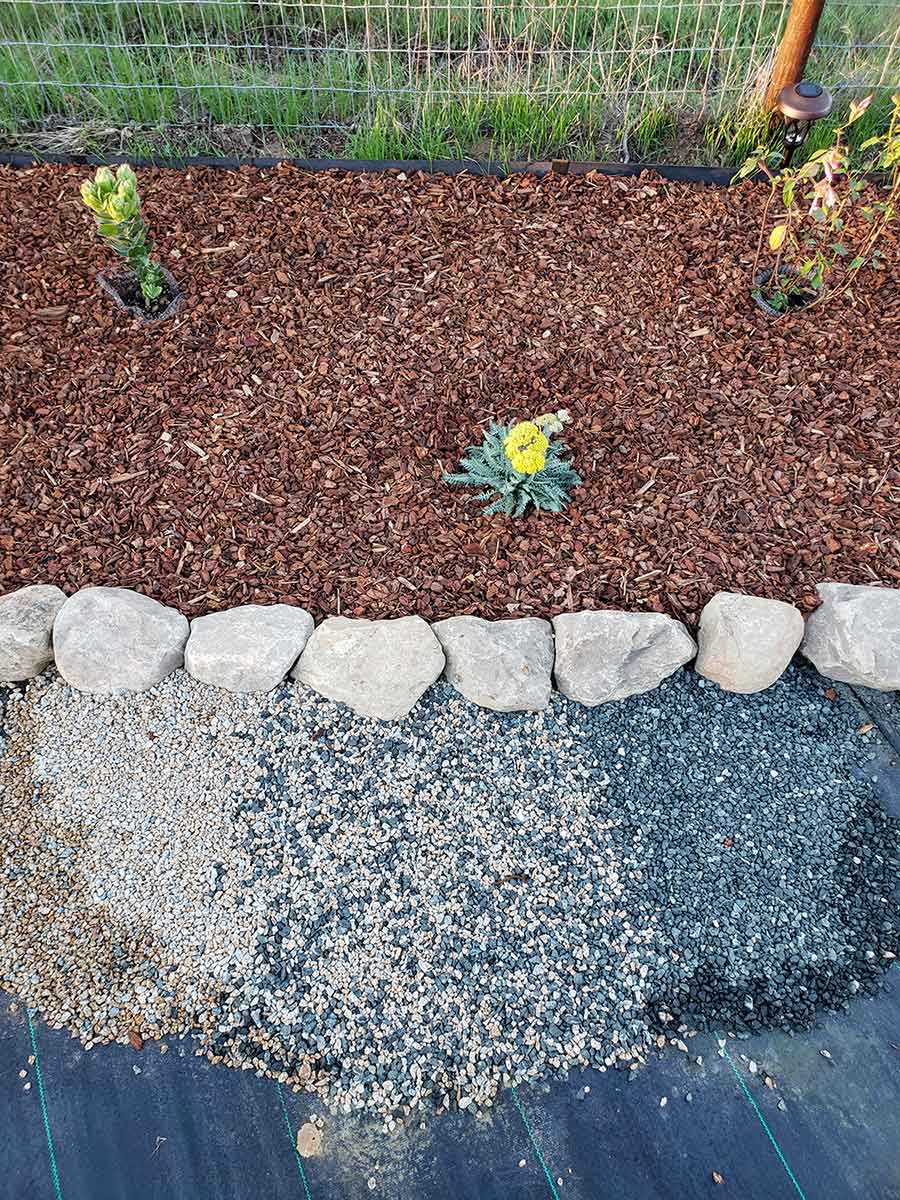 small portion of backyard filled with mulch and flowers bordered by rocks small portion of backyard filled with mulch and flowers bordered by rocks