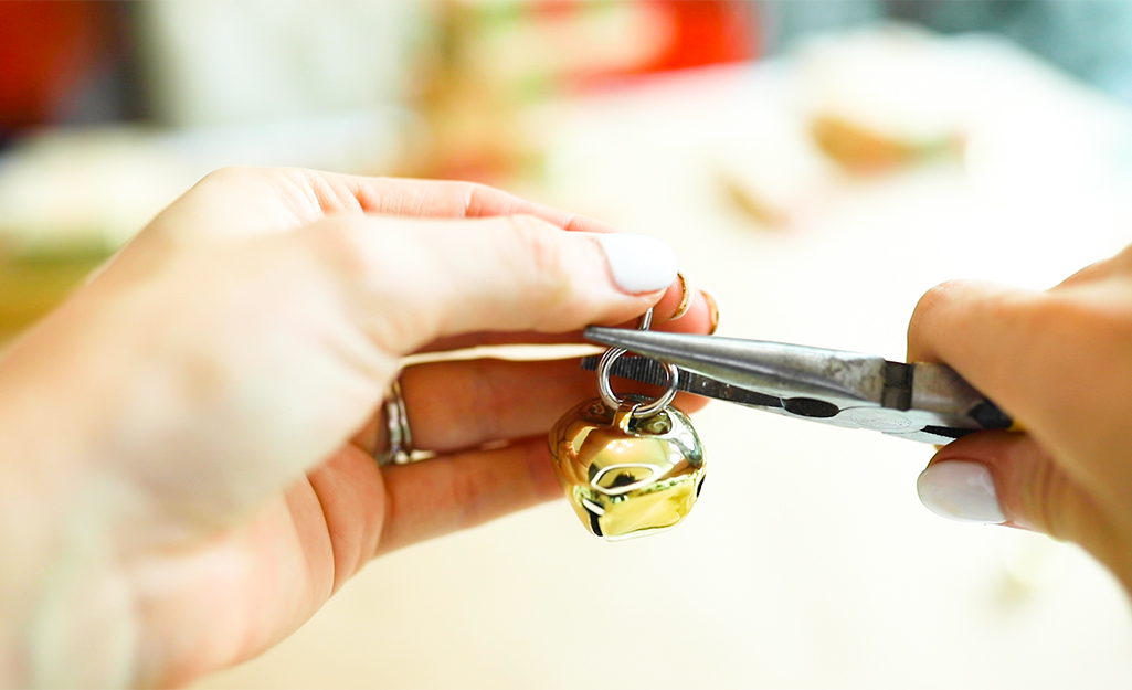 Someone inserting a eye screw into a jingle bell.