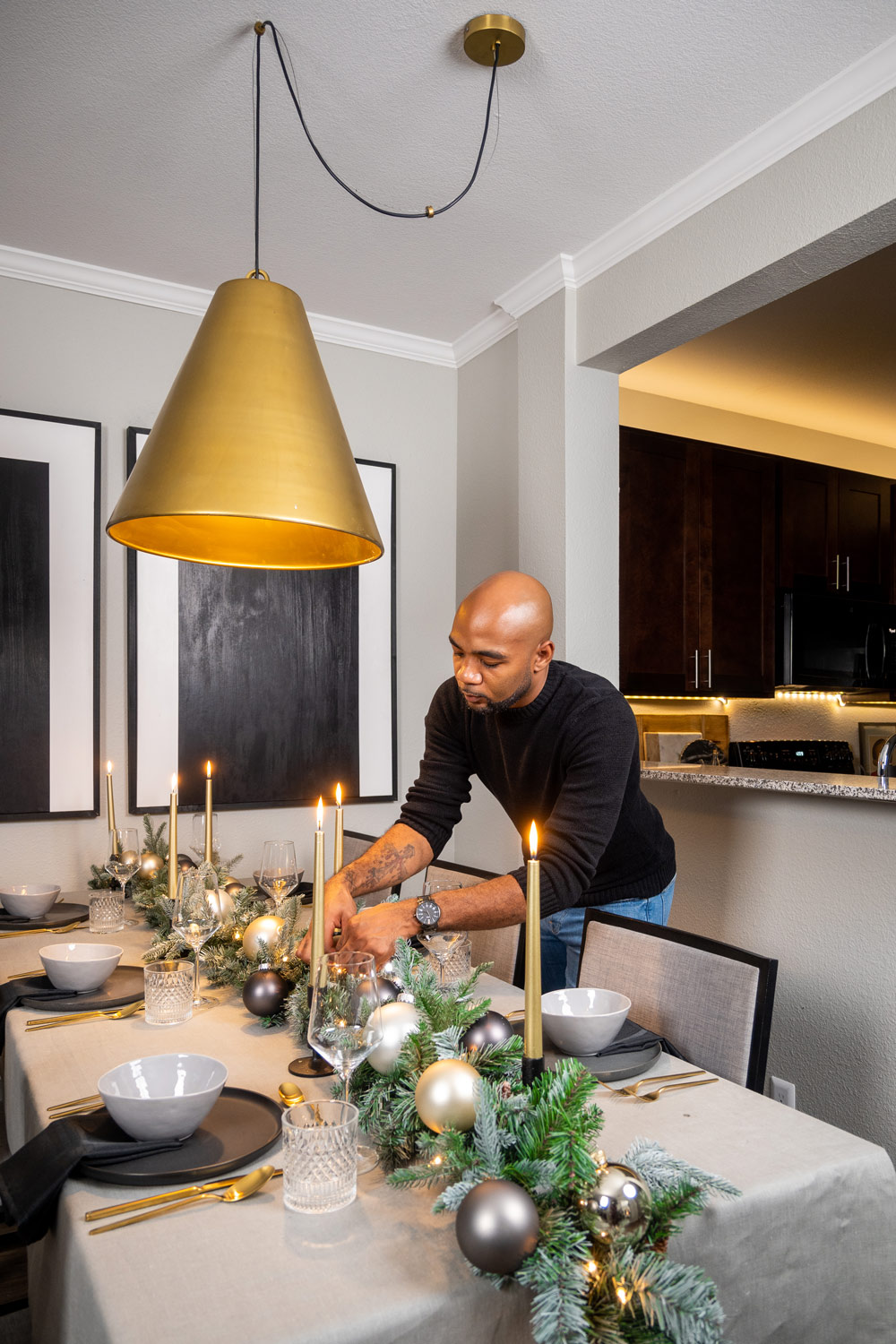 Man standing next to table adjusting holiday-themed centerpiece Man standing next to table adjusting holiday-themed centerpiece