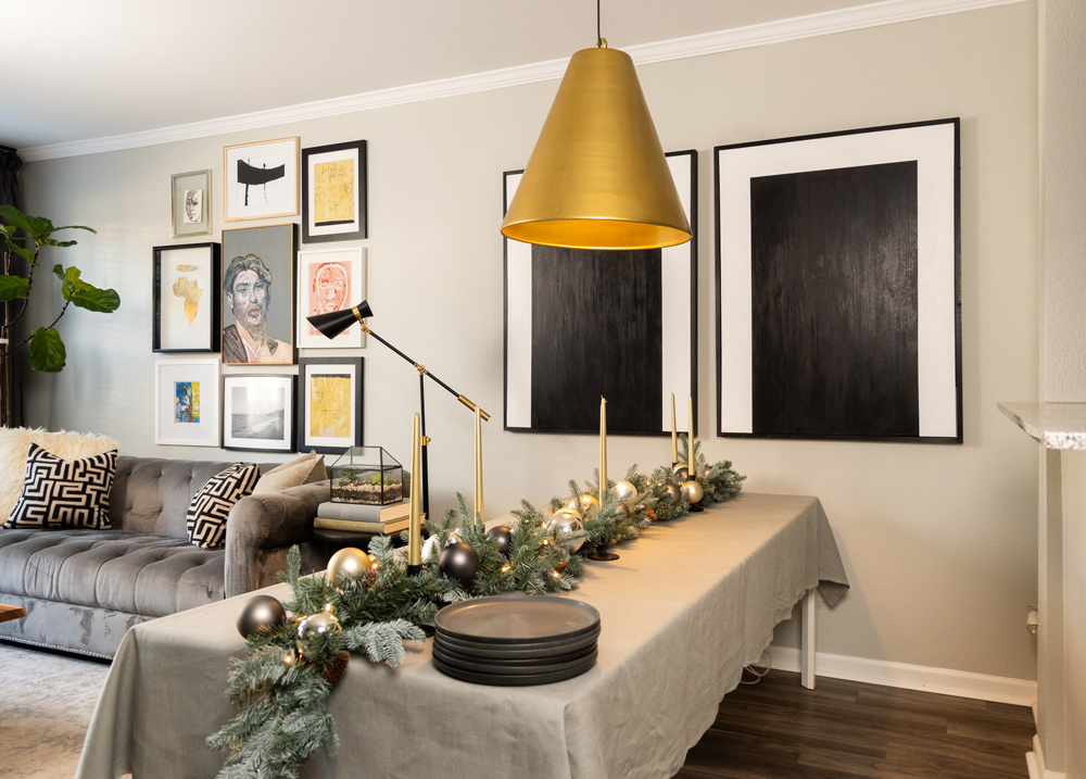 Holiday table setting in a dining room with plates stacked on table and a gold pendant light hanging above Holiday table setting in a dining room with plates stacked on table and a gold pendant light hanging above