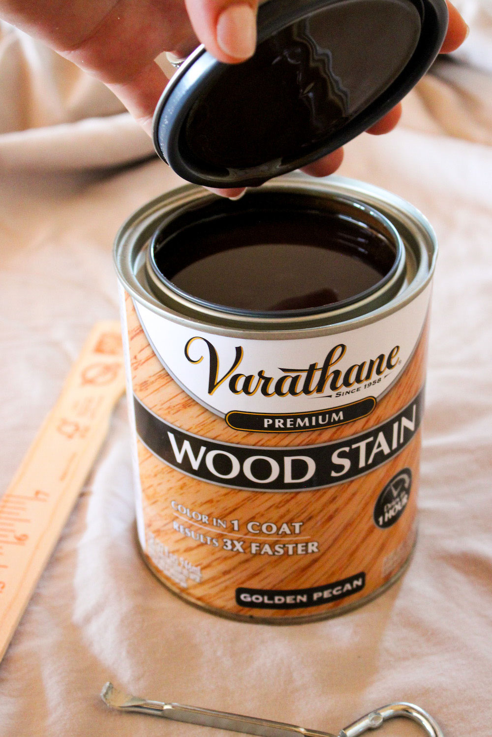 A person opens the top of a can of Varathane premium wood stain.