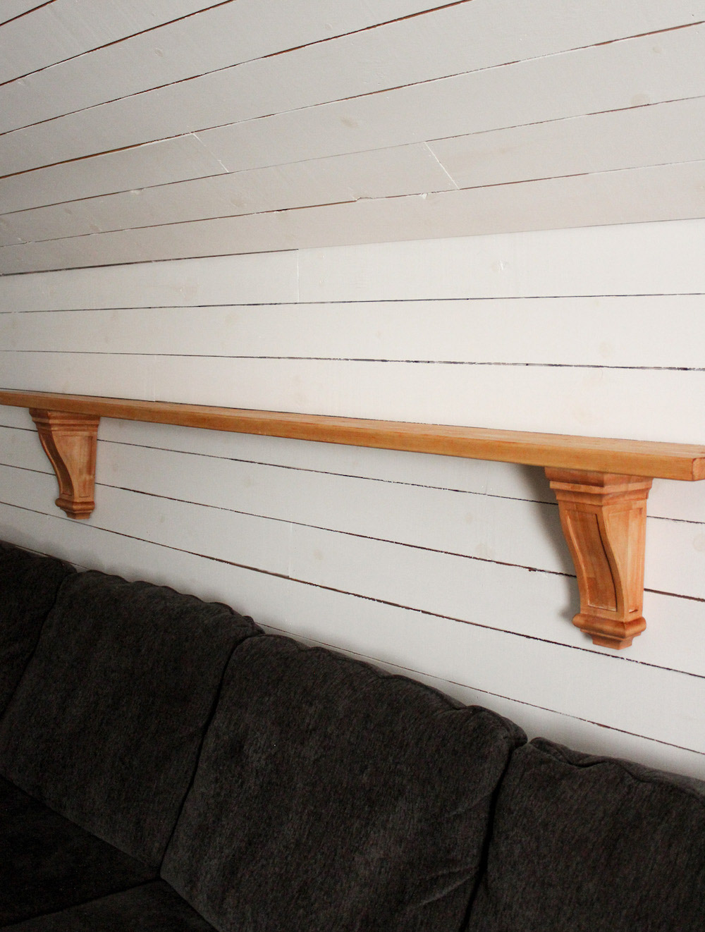 A completed large wall shelf stained with Varathane premium hangs on a white shiplap wall.