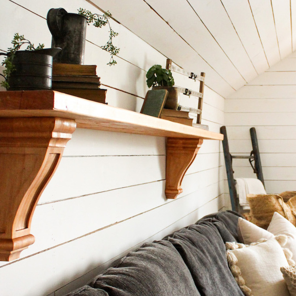 A Varathane premium stained wood shelf hangs on a white shiplap wall.