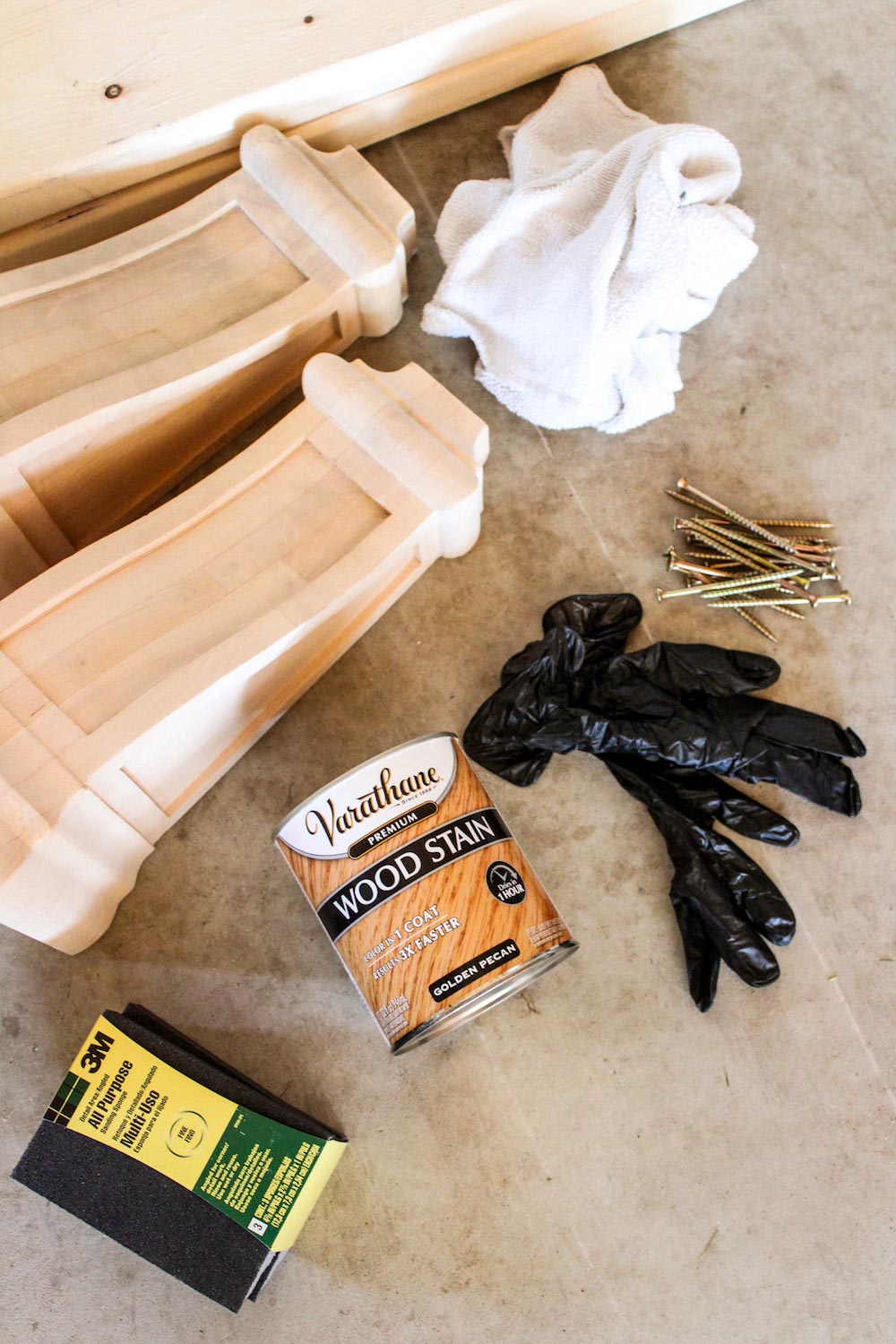 Various tools and materials needed to build and stain a wooden wall shelf.