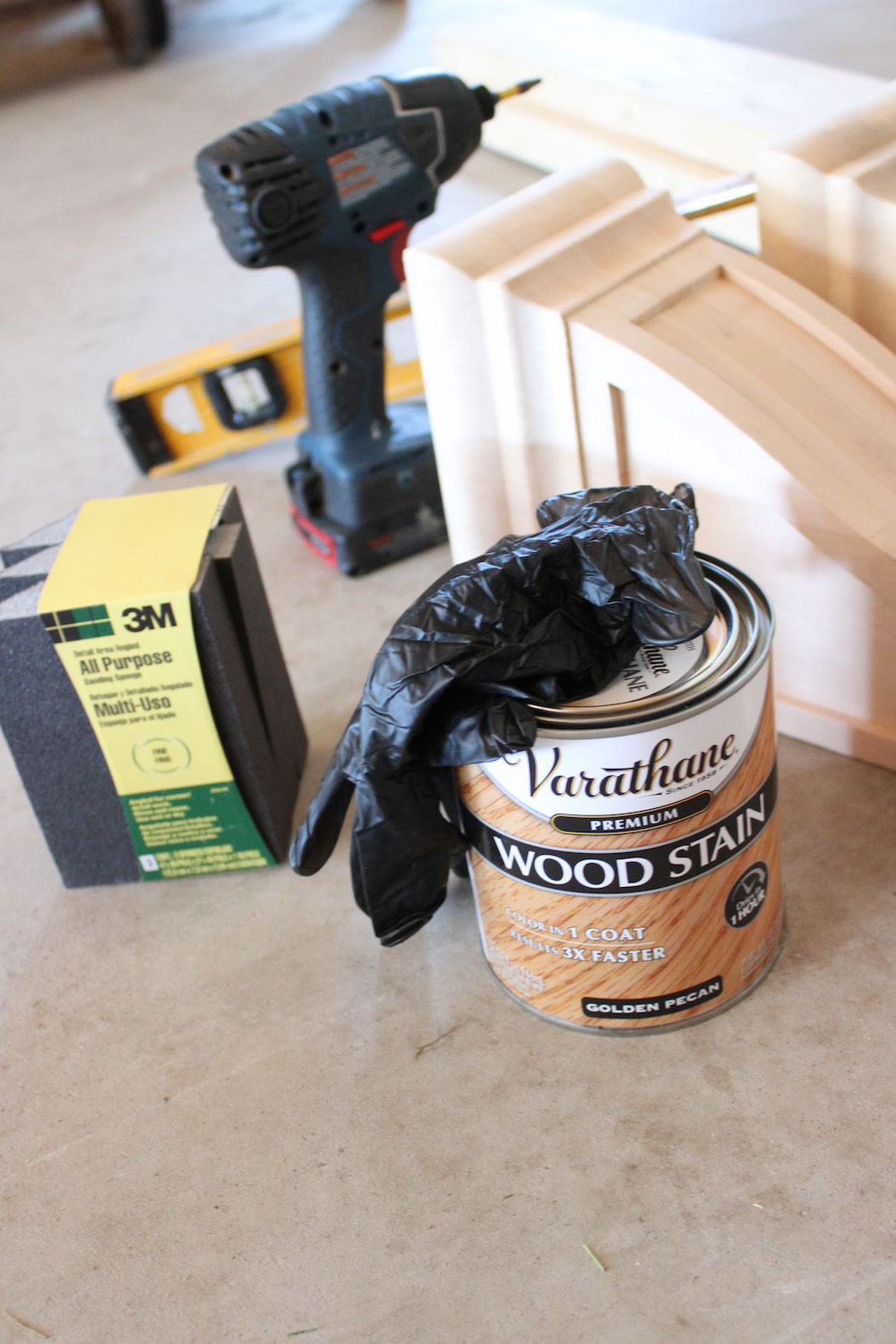 Various tools and materials needed to build and stain a wood shelf such as Varathane wood stain.