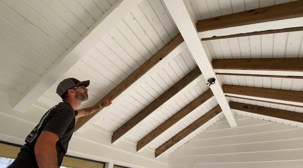 A man pushing on the installed ceiling beams.