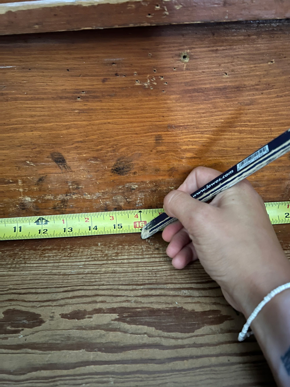 A person using a pencil and tape measure.