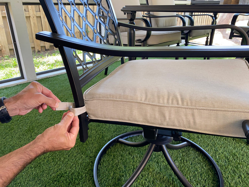 A man’s hands tying a cushion strap to a patio chair. A man’s hands tying a cushion strap to a patio chair.