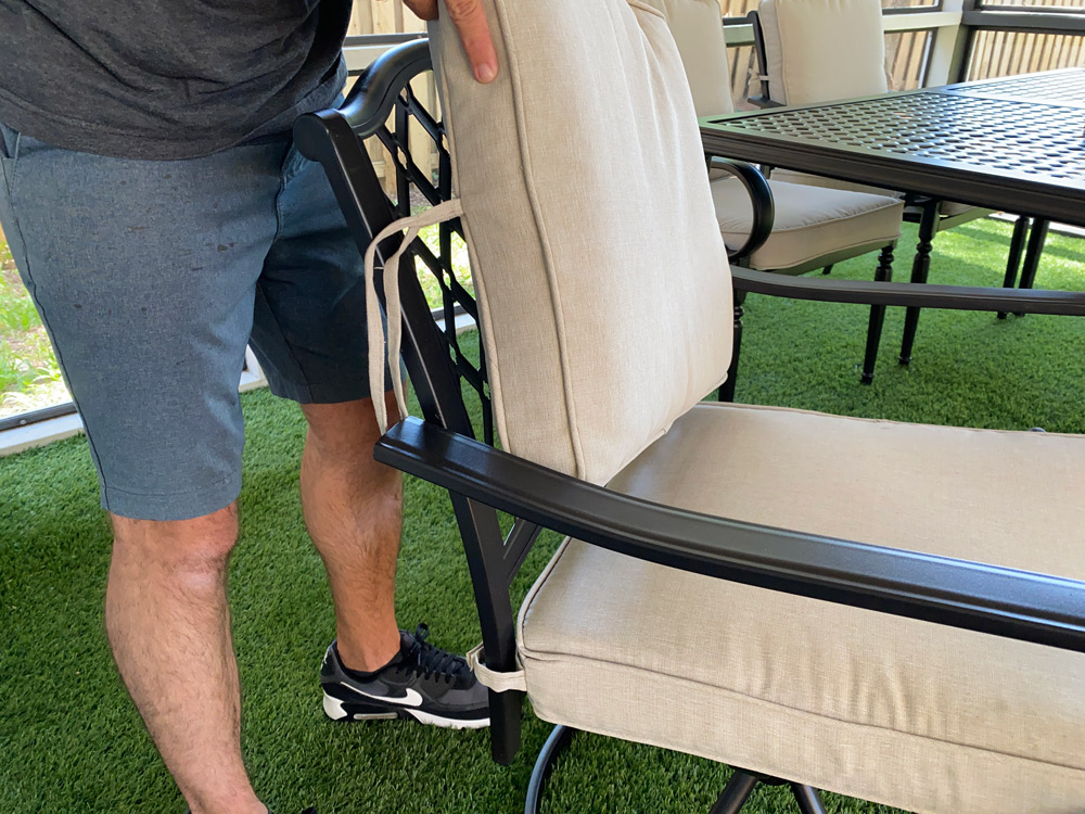A man setting a back cushion on a patio chair. A man setting a back cushion on a patio chair.