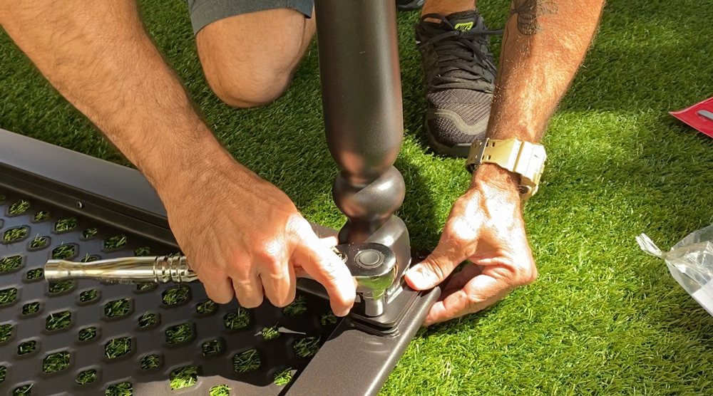 A man using a wrench to attach a leg to a tabletop. A man using a wrench to attach a leg to a tabletop.