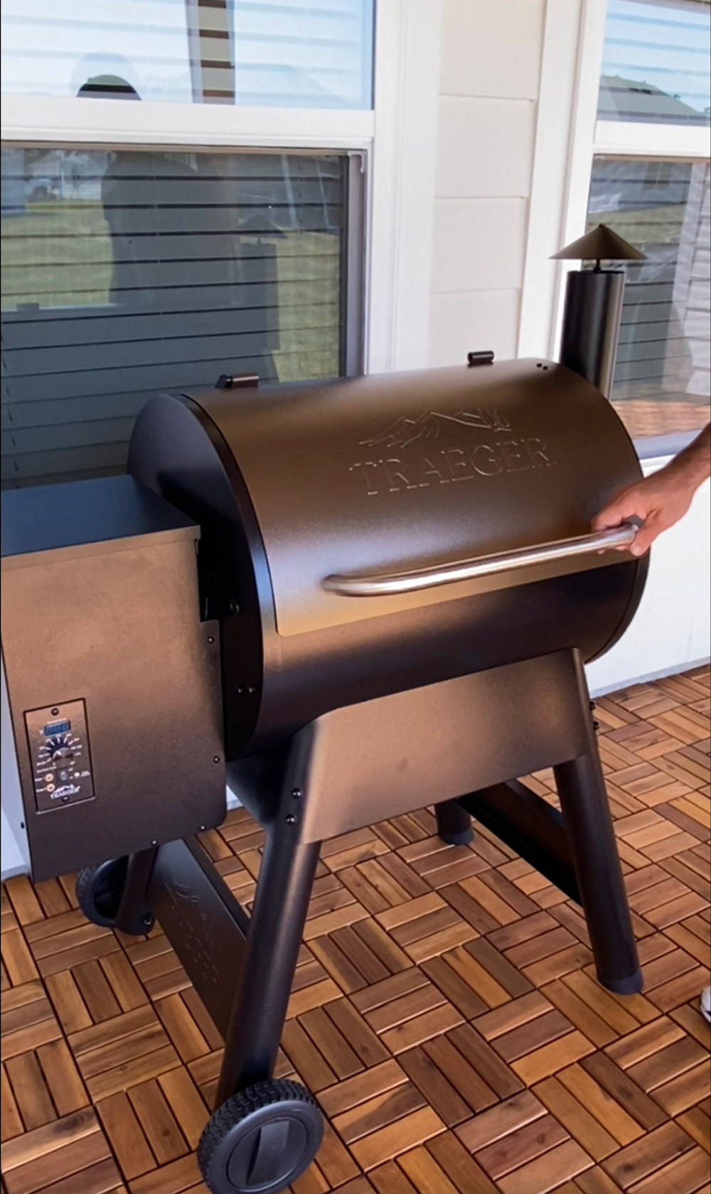 A person holding a bronze Trager grill. A person holding a bronze Trager grill.