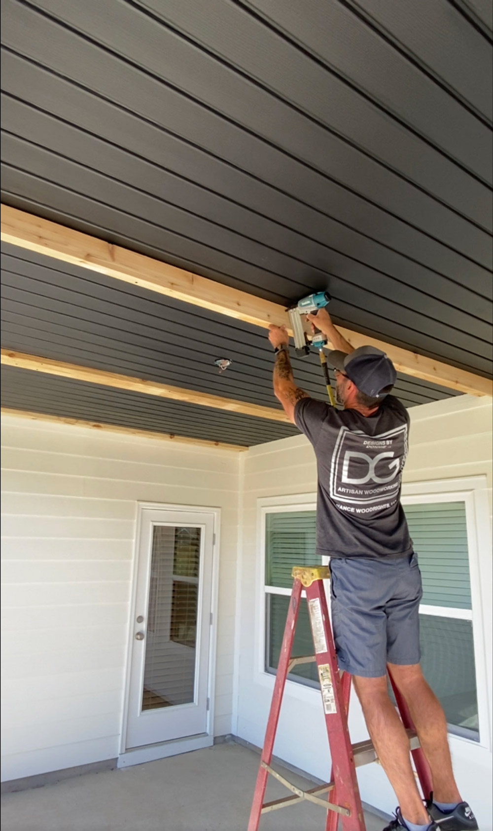 A man standing on a ladder, installing wood ceiling beams. A man standing on a ladder, installing wood ceiling beams.