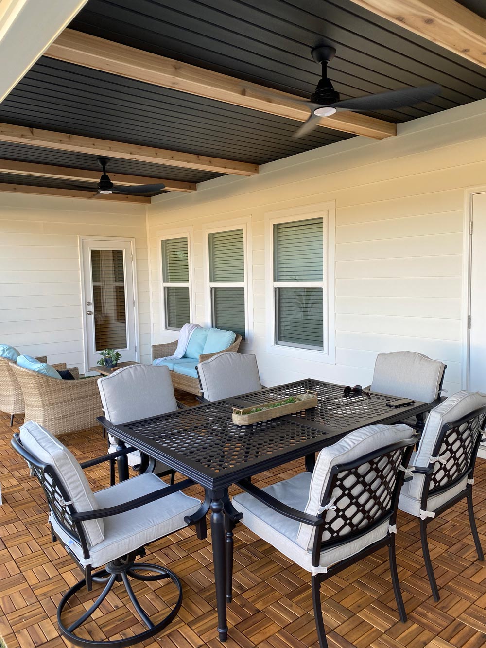 Completed patio space with a black table set, wood flooring, and wicker patio set. Completed patio space with a black table set, wood flooring, and wicker patio set.